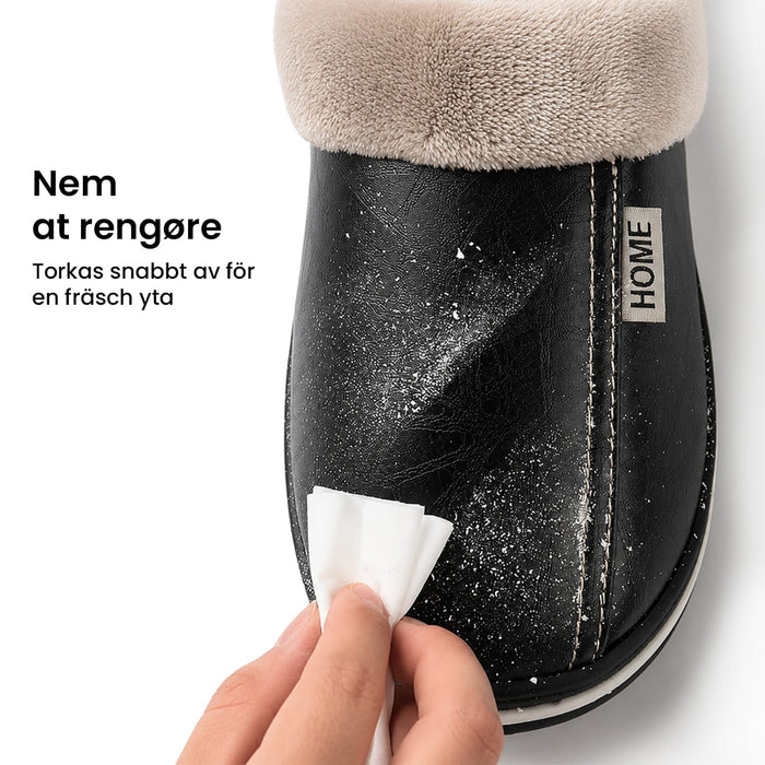 Man tørrer et par sorte, foret indendørs hjemmesko af læder af med en hvid klud.