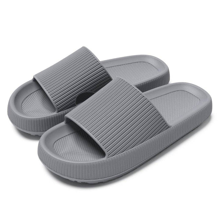 Grå hjemmesko med memory foam, stødabsorberende såler og strukturerede bånd, der sikrer komfort.