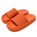 Stødabsorberende orange hjemmesko med brede remme og sål af memory foam, vist på hvid baggrund.
